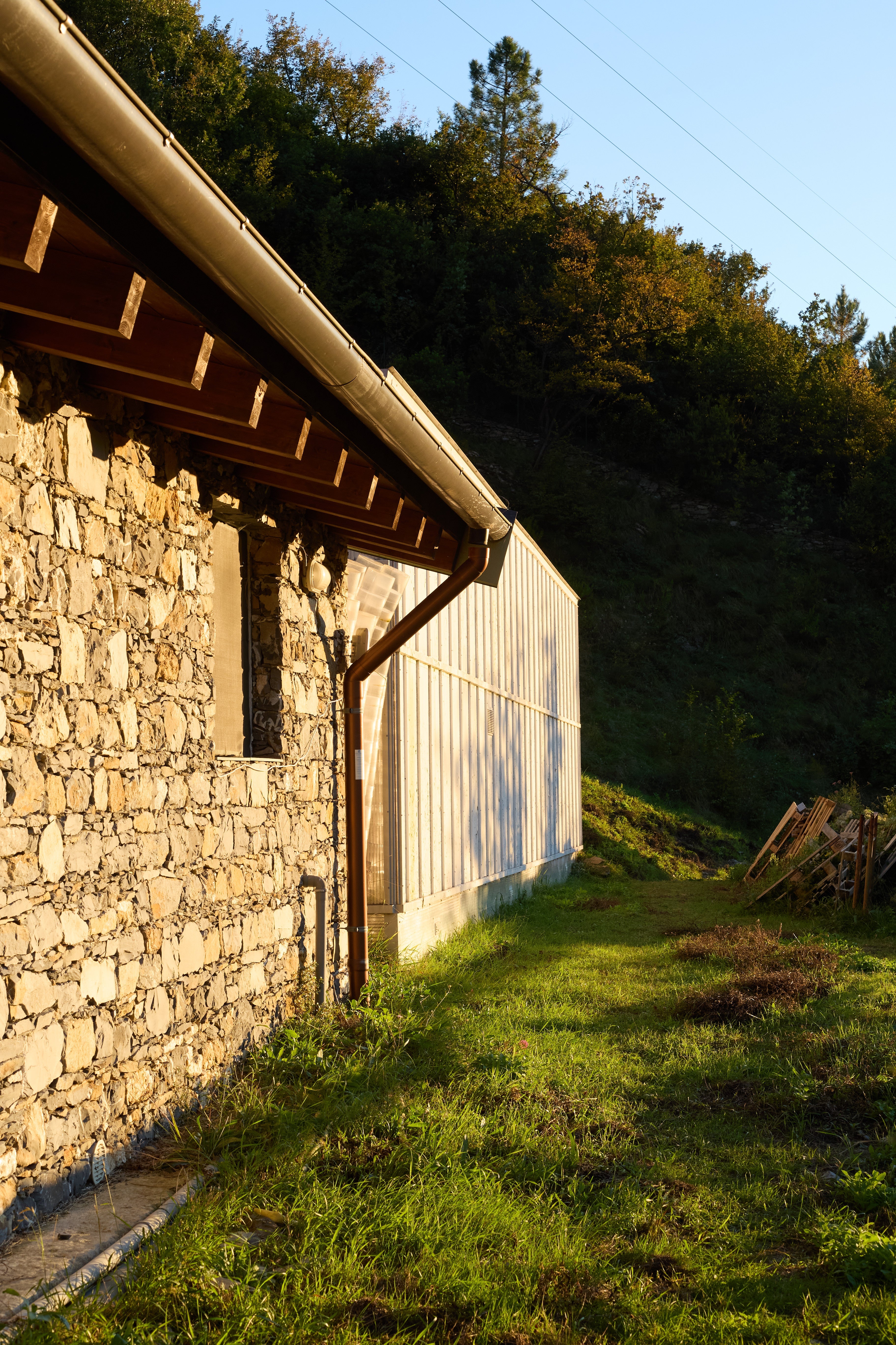 Struttura agricola in pietra e metallo immersa nel paesaggio collinare ligure al tramonto
